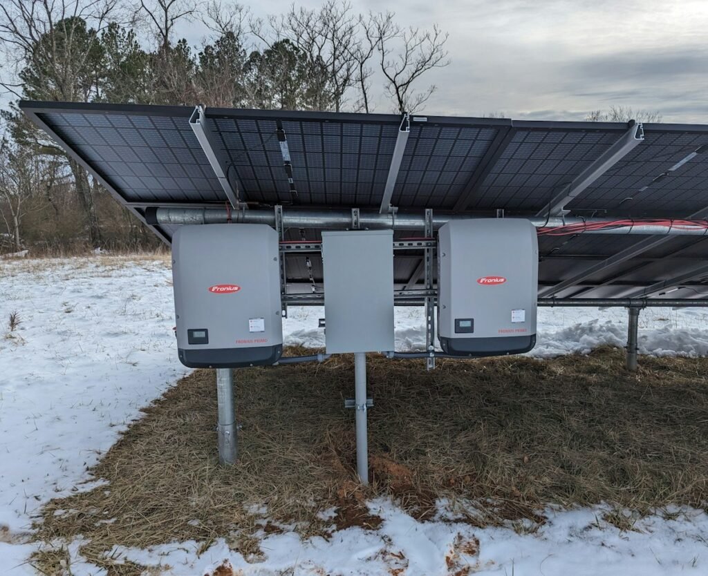 Solar inverters installed beside a ground-mounted photovoltaic array
