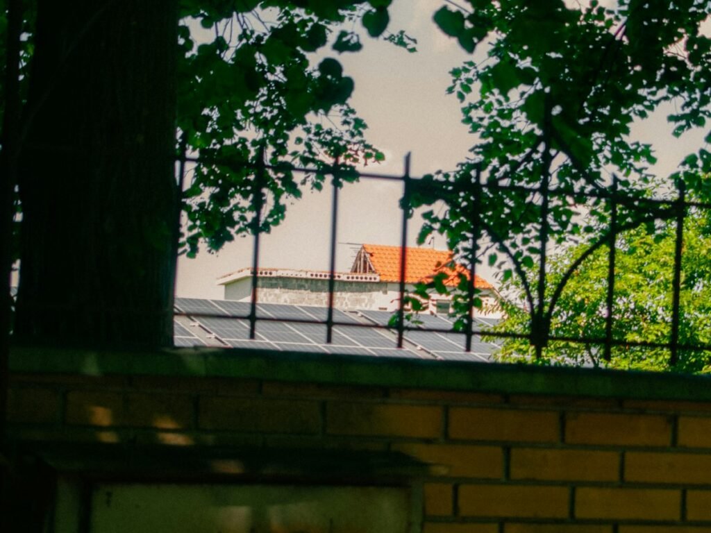 Rooftop solar panels behind a brick wall and fence